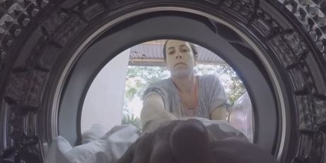Žena ubacuje odjeću u perilicu rublja