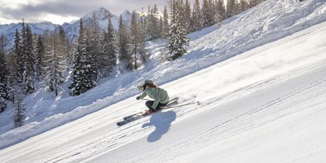 Skijanje na savršeno uređenim stazama - široki zavoji i pogled na alpske vrhove