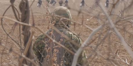 Vojnik u polju promatra migrante