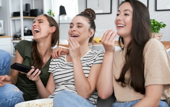 Djevojke se smiju dok gledaju televiziju