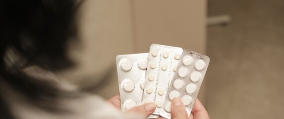 Žena srednjih godina koja drži nekoliko raznih tableta