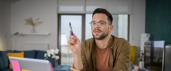 Muškarac za računalom s otvorenom knjigom