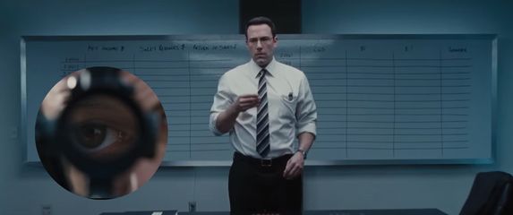 glumac ben affleck u filmu računovođa stoji u uredu i nišani