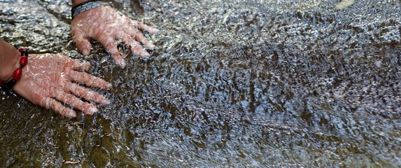 Žena s dlonovima uronjenim u rijeku