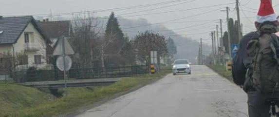 Muškarac s božićnom kapicom na biciklu sa svinjom u torbi