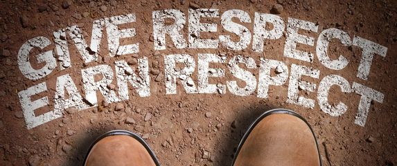 čizme i natpis u zemlji na kojem piše give respect earn respect