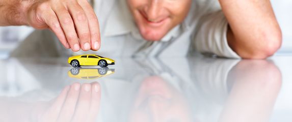 Muškarac se igra s minijaturnom igračkom sportskog automobila