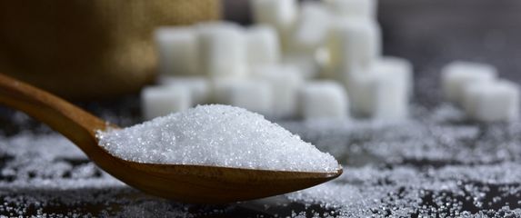 Žlica šećera i šećer u pozadini