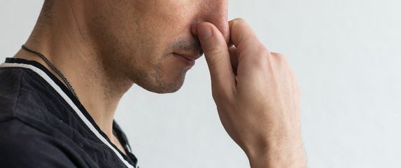 Muškarac koji se drži za nos