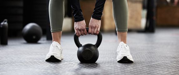 Žena vježba s utegom u teretani