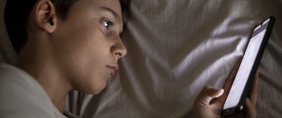 Dječak surfa na mobitelu u krevetu, ilustracija