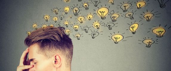 Muškarac koji razmišlja i žarulje koje predstavljaju ideje