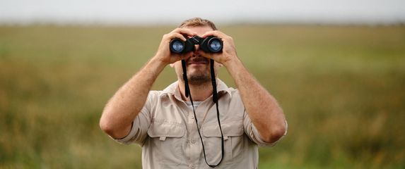 Muškarac koji gleda kroz dvogled