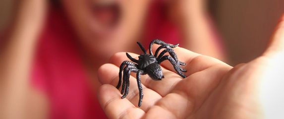 Plastični pauk u ruci i žena s izrazom straha na licu