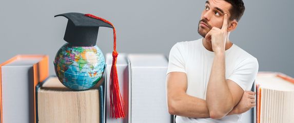 Knjige i globus s kapom uz muškarca koji razmišlja