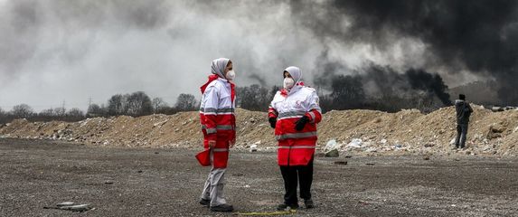 Pripadnice Iranskog društva Crvenog polumjeseca stoje pored crnog sukljajućeg dima nakon zračnih napada