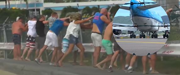 Mlažnjak pri polijetanju i turisti koji se drže za ogradu