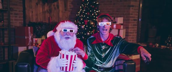 Djed Božičnjak i patuljak pomagać gledaju filmove s 3d naočalama i kokicama