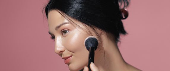 Žena nanosi puder kistom