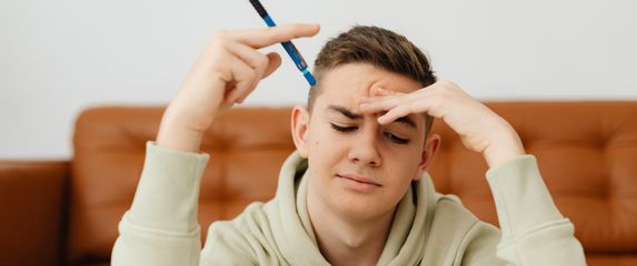 Mladić koji razmišlja s olovkom u ruci