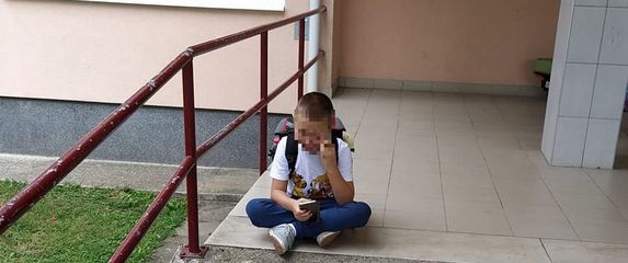 Dječak ispred škole čeka pomoćnika u nastavi (Foto: Facebook)