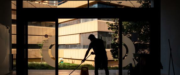 muškarac čisti ispred ulaza u zgradu