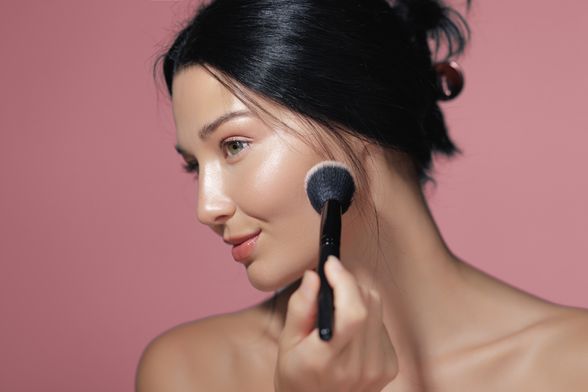 Žena nanosi puder kistom