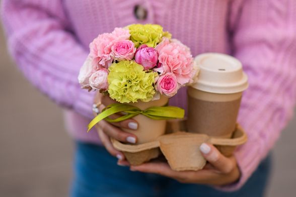 Žena drži cvijeće i kavu