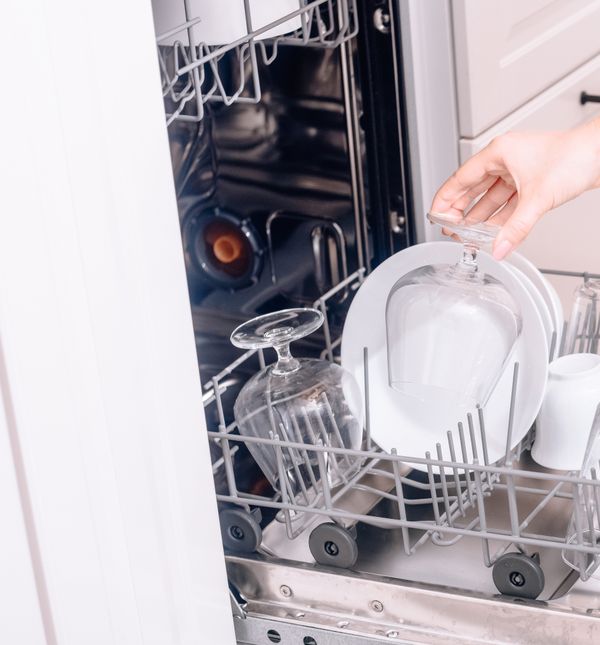 Žena puni perilicu posuđa