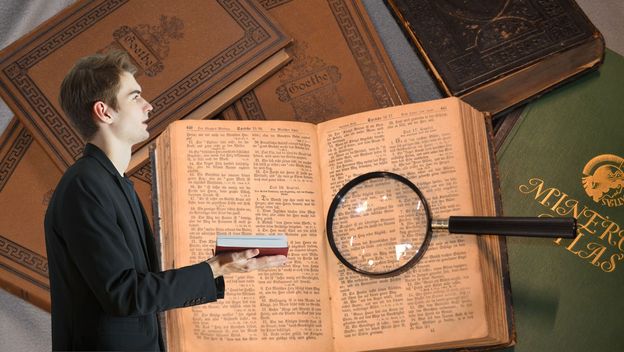 Muškarac s otvorenom knjigom i knjige s povećalom