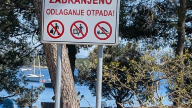 Deponij ispod znaka za zabranu odlaganja otpada