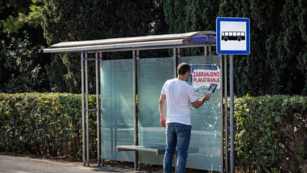 Muškarac koji uklanja natpis zabranjeno plakatiranje s autobusne stanice