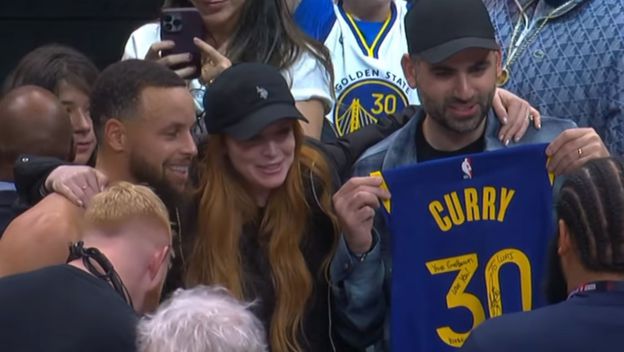 košarkaš Steph Curry i Lindsey Lohan sa suprugom Baderom Shammasom pozira za sliku s dresom Curryja i posvetom na brojevima