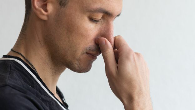 Muškarac koji se drži za nos