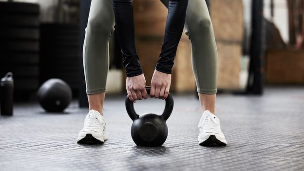 Žena vježba s utegom u teretani