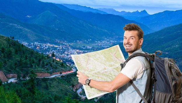 Grad u planinama i turist s ruksakom i kartom