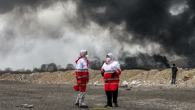 Pripadnice Iranskog društva Crvenog polumjeseca stoje pored crnog sukljajućeg dima nakon zračnih napada