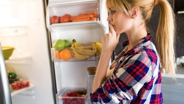 Djevojka zamišljeno gleda u hladnjak