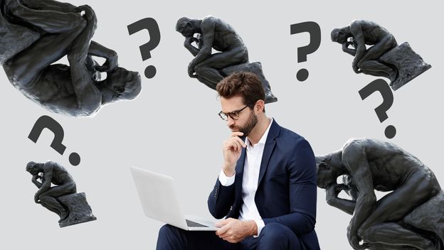 Muškarac koji razmišlja pred računalom i kip mislioca