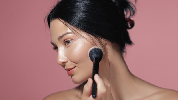 Žena nanosi puder kistom