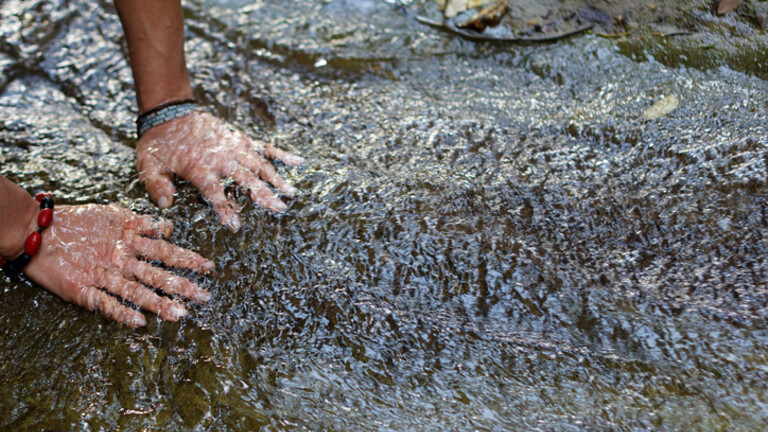 Žena s dlonovima uronjenim u riječicu
