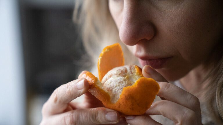 Žena njuši oguljenu mandarinu