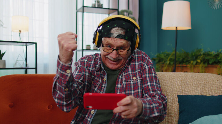Stariji muškarac igra računalnu igru na mobitelu
