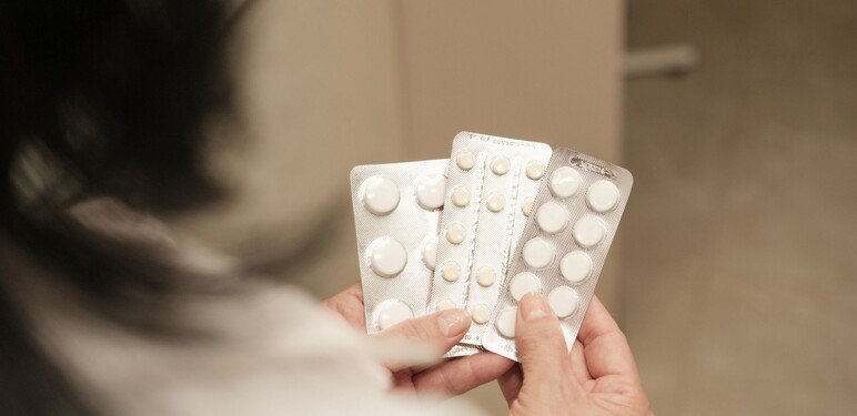 Žena srednjih godina koja drži nekoliko raznih tableta