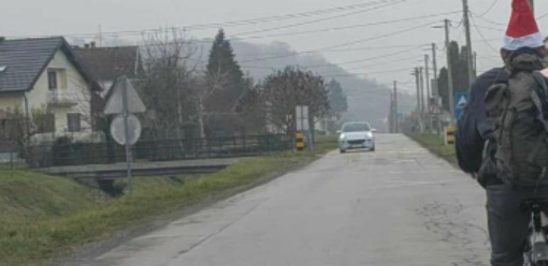 Muškarac s božićnom kapicom na biciklu sa svinjom u torbi