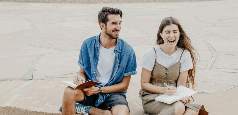 muškarac i žena sjede i pričaju dok se žena smije