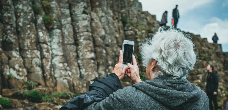 stariji sjedi muškarac kako na izletu u prirodi fotografira krajolik