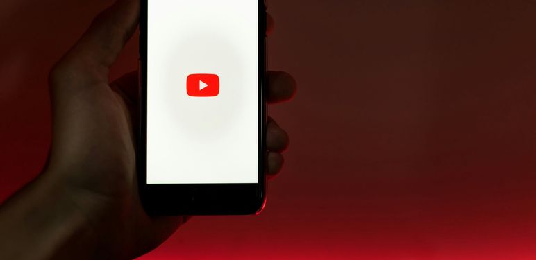 ruka koja drži mobitel s upaljenim zaslonom učitavanja youtubea