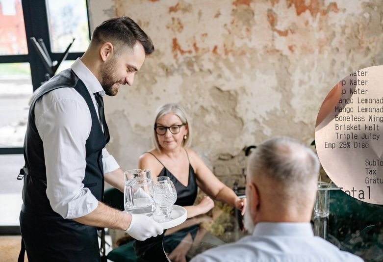 Konobar kako poslužuje ljude i račun iz restorana