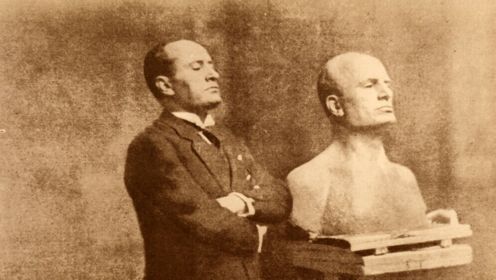 Benito Mussolini pozira uz svoju bistu